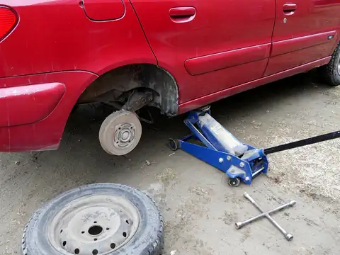 Krikoyla kaldırılmış aracın tekerleği sökülmüş, yerde lastik ve bijon anahtarı